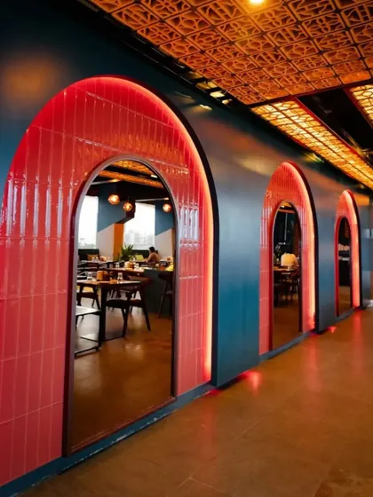 A key design feature at Bramble is this series of bold, red-tiled arches with integrated backlighting. They create a visually stunning corridor that adds depth and character to the restaurant's interior layout.