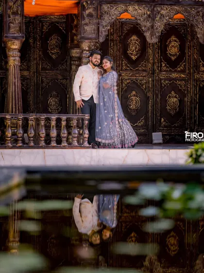 A stunning reflection shot of a couple in elegant traditional wear. The water creates a perfect mirror image, adding an artistic touch to this beautiful portrait.