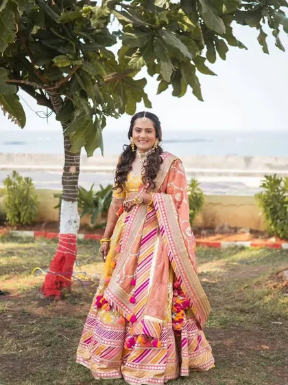The bride looking beautiful by the sea. Her Haldi outfit and her fresh, dewy makeup are perfect for a beachside wedding celebration.