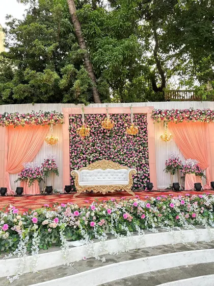 A daytime view of the classic reception stage, showcasing the beautiful peach drapes and the abundance of fresh flowers.