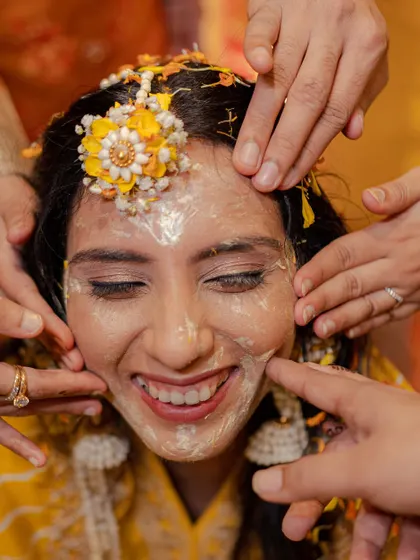A bride's radiant smile during her Haldi ceremony. Even when covered in paste, her happiness shines through, and we make sure to capture it.