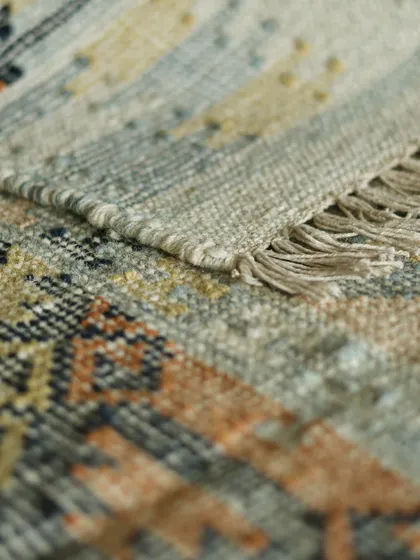 Another detail shot of a handwoven dhurrie, focusing on the tightly woven edge. The subtle variations in color and texture are the signature of an artisan-made piece, crafted for a lifetime of use.