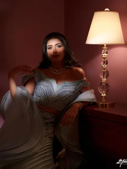 A moody, glamorous portrait of a bride in a stunning structured gown. The single lamp as a light source creates a dramatic, cinematic feel, reminiscent of old Hollywood glamour.