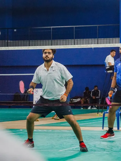 Players ready to receive a serve during a men's doubles match at a corporate event. The setup includes certified referees and proper court markings, ensuring fair and official gameplay.
