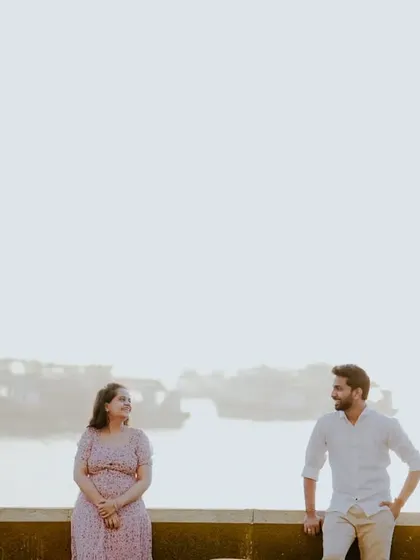 A wide shot of the couple with the hazy Mumbai harbor in the background, creating a soft and romantic atmosphere.