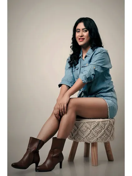 A relaxed and confident studio portrait. The denim-on-denim look and the model's easy smile create a friendly and approachable vibe.