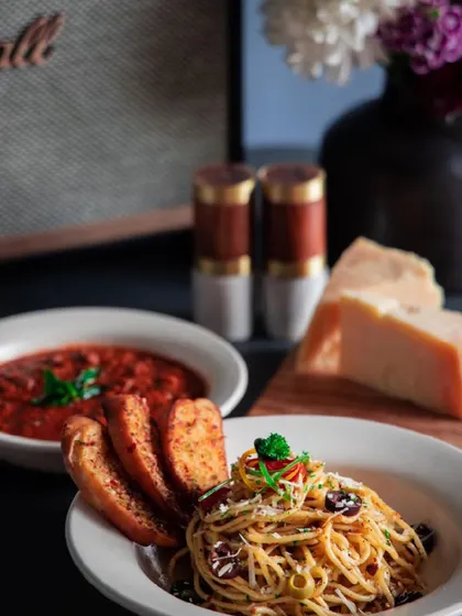 A classic Italian meal featuring spaghetti aglio e olio and a side of arrabbiata sauce with garlic bread.