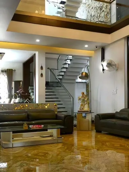 A view of a spacious, double-height living room we designed, featuring marble flooring and a modern staircase. This project showcases our work on a larger, more luxurious scale.