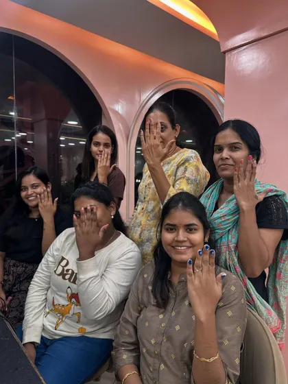 A group of happy students showing off their freshly done nails at the end of a practice session.