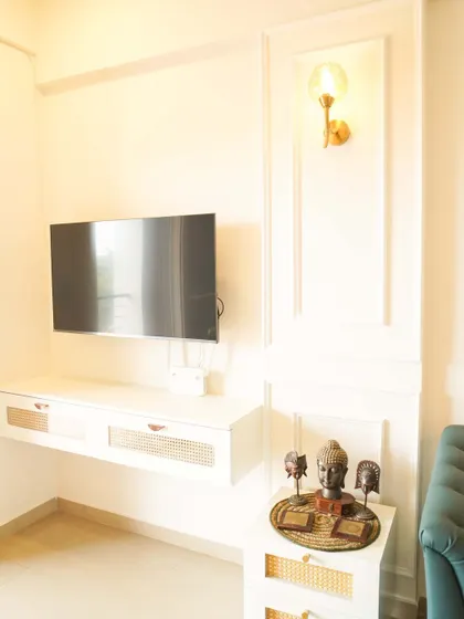 A simple and elegant TV setup with a floating console featuring cane webbing on the drawers. The wall molding and single sconce add a touch of sophistication.