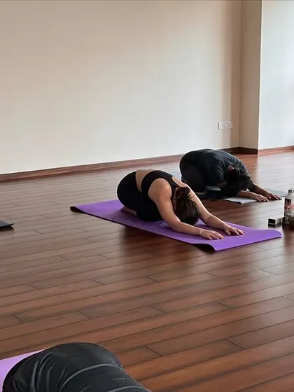 Where the mat meets the moment, and every breath takes you deeper. A student rests in Balasana (Child's Pose).