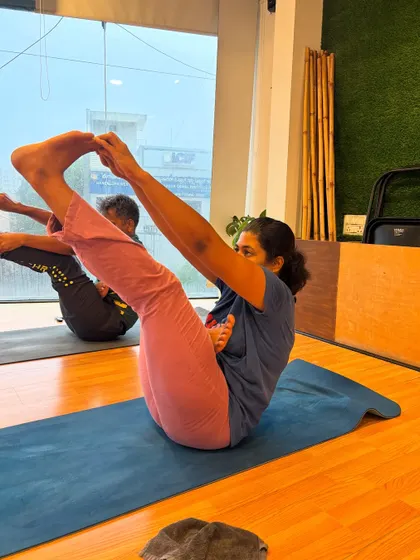 A student holds a strong boat pose, engaging her core and finding her balance.