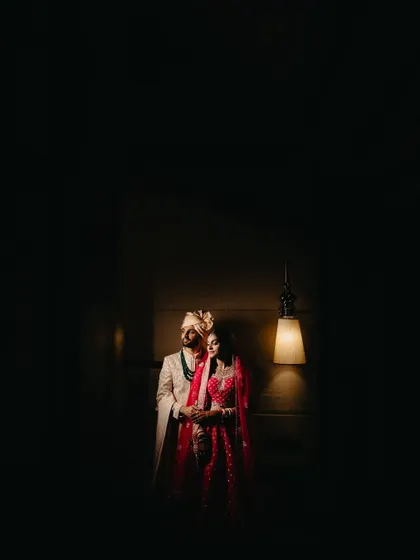 A dramatic, wide portrait using negative space to create a cinematic and artistic feel. The single light source highlights the couple beautifully.
