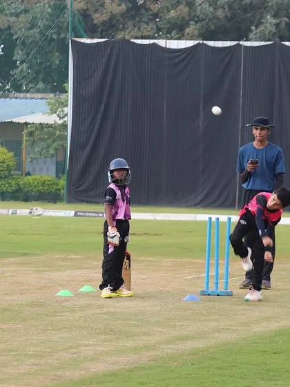 A U-10 player practices bowling in the nets, learning the fundamentals of a good, repeatable action under supervision.