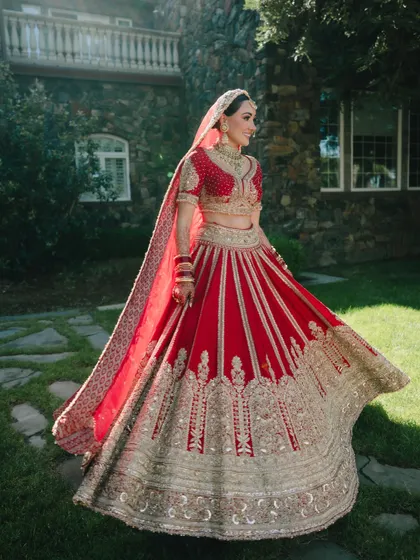 The bride twirls in her traditional red Sikh wedding lehenga, showcasing its beautiful embroidery and flow against the backdrop of a California castle.