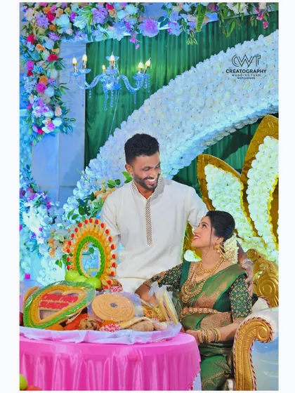 Capturing a candid, smiling moment between the couple at their baby shower. The elaborate floral decorations and traditional items on the table show the festive atmosphere of the event.