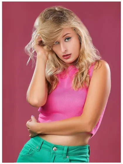 A vibrant and colorful portrait with a pink top and green pants against a magenta background. This shot is full of energy and perfect for a youthful fashion brand.