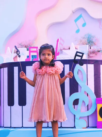 The birthday girl takes center stage, holding musical note props in front of a giant piano backdrop. Her joy is the perfect reflection of a party designed around her love for music.