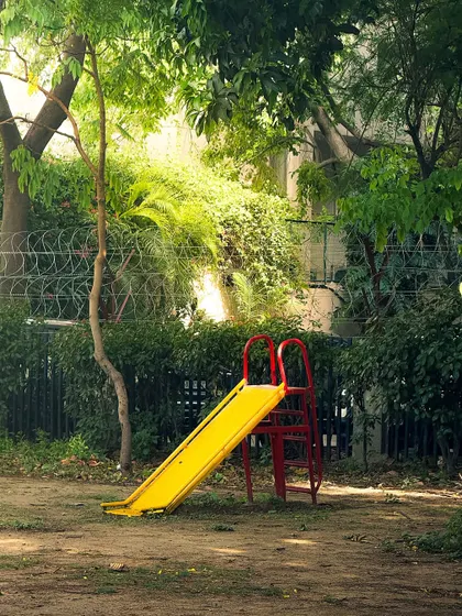 A simple yellow slide in a park, bathed in sunlight. This image is part of a series on childhood nostalgia, finding beauty and memories in everyday objects.