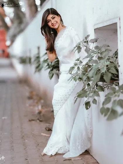 An elegant street portrait of an actress in a white saree. This shot blends traditional attire with a modern, urban environment.