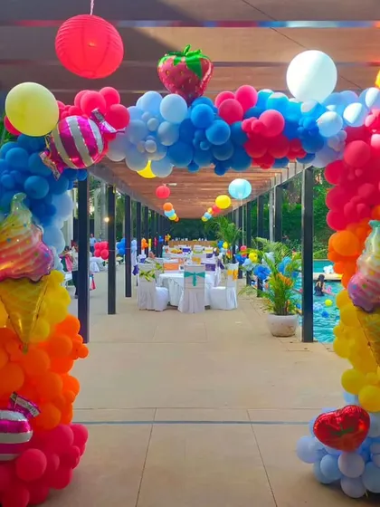 A grand balloon archway decorated with ice cream and strawberry foil balloons creates a fun and inviting entrance to this outdoor pool party.