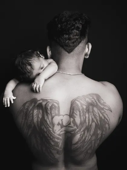 A powerful black and white portrait capturing the bond between a father and his newborn. The dramatic lighting and composition create a truly artistic and memorable image.