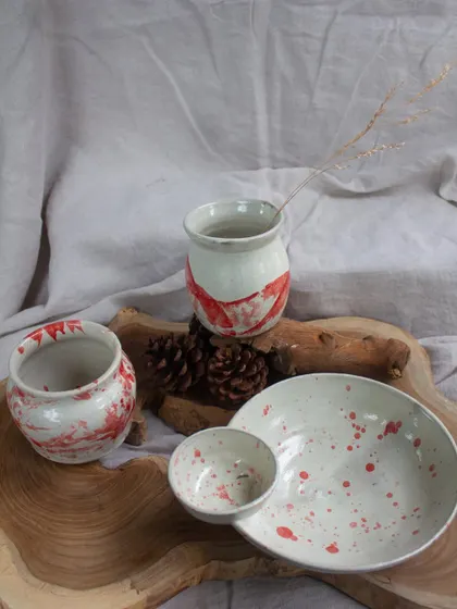A collection of student work with red and white marbled and splattered slip decoration.