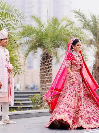 A dynamic shot of the bride twirling in her vibrant pink lehenga, creating a beautiful sense of motion and joy as the groom looks on with a smile.
