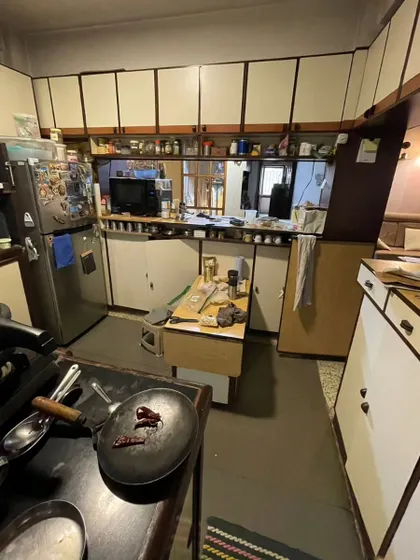 **BEFORE:** The original kitchen, showing its cramped layout and dated white-and-brown cabinets.