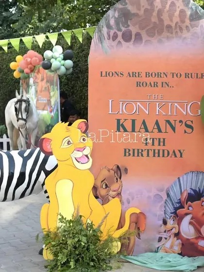 A welcome display for the Lion King party, featuring character cutouts, animal props, and a balloon garland in theme-appropriate colors.
