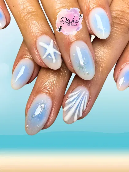 Beach in a manicure. These dreamy nails feature a soft blue base with 3D seashells and starfishes for the perfect summer escape.