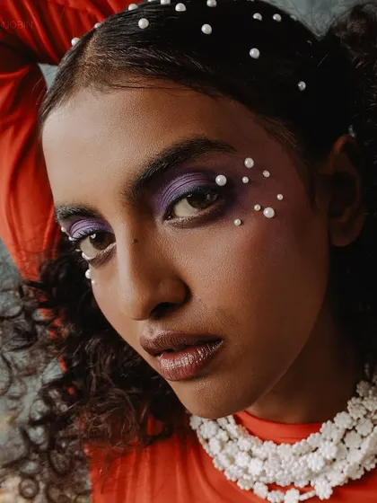 A beauty shot from the same series, focusing on the pearl-adorned makeup and hair, which complements the pearl necklace.