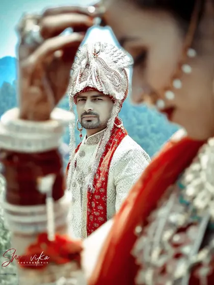 A creative shot focusing on the groom through the bride's veil. This artistic approach adds a layer of depth and intimacy to the wedding portrait.