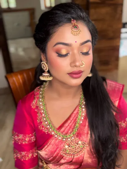 This bride's look for her Muhurtham features soft golden eyeshadow to match her jewelry, paired with a beautiful magenta lip that brings out the color of her silk saree.