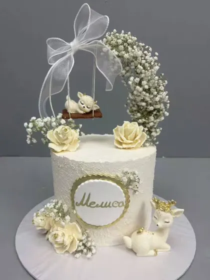 A cute yet elegant custom cake adorned with flowers and a sleeping deer figurine.