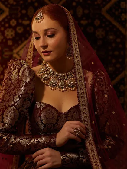 A truly regal look featuring a heavy Kundan and pearl necklace. This piece is perfect for a bride who wants to make a grand statement, pairing beautifully with a rich, dark-colored lehenga.