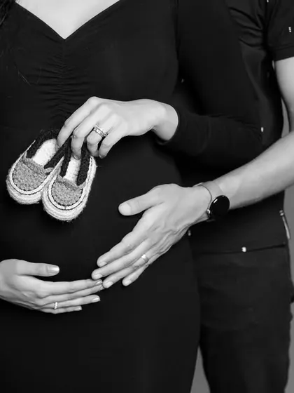A classic black and white close-up on the bump, with baby shoes and the parents' hands creating a beautiful composition.
