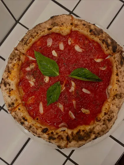 A top-down view of the Marinara pizza, showcasing its vibrant red sauce and fresh basil.