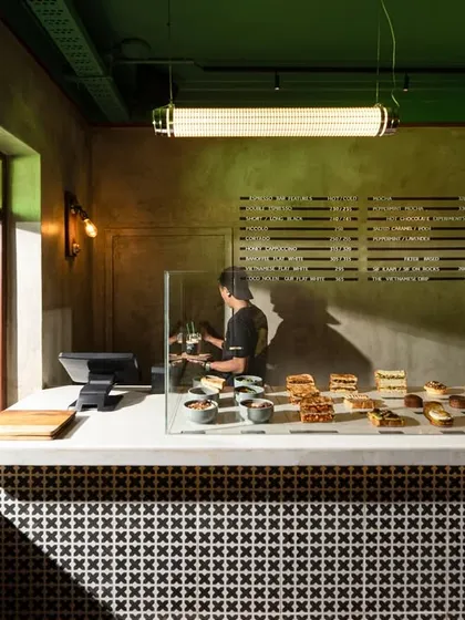 The coffee counter features a bold, graphic tile pattern that contrasts with the rustic, lime-washed walls. This blend of patterns and textures is central to my retro-modern approach, creating visual interest and a unique brand identity for the space.