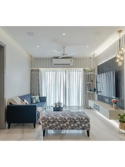 This living room captures my signature style: clean, modern, and comfortable. I used vertical fluted panels and integrated LED lighting to add texture and height to the space, while the floating TV unit keeps the floor clear and creates an airy feel. The pop of blue in the sofa and the geometric ottoman bring personality into the neutral palette.