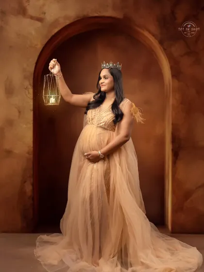 A queenly portrait featuring a mom-to-be holding a lantern, symbolizing the light of new life, while wearing a crown and elegant gown.
