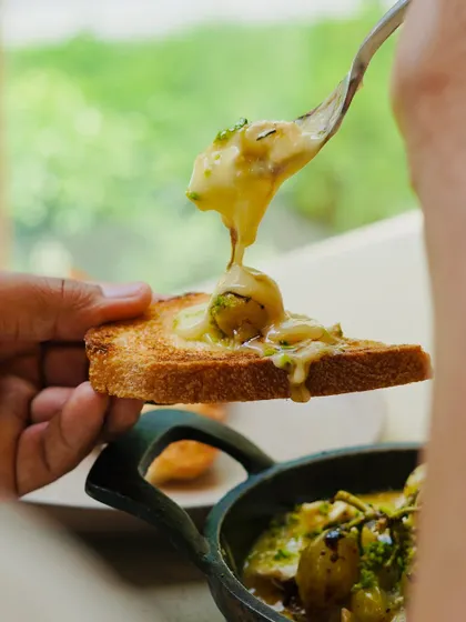 This is what happens when incredible local ingredients come together. We take artisanal brie, melt it until bubbly with farm-grown herbs, and top it with oven-blistered Kumaoni grapes. It's a truly unique appetizer, perfect for sharing over sourdough toast.