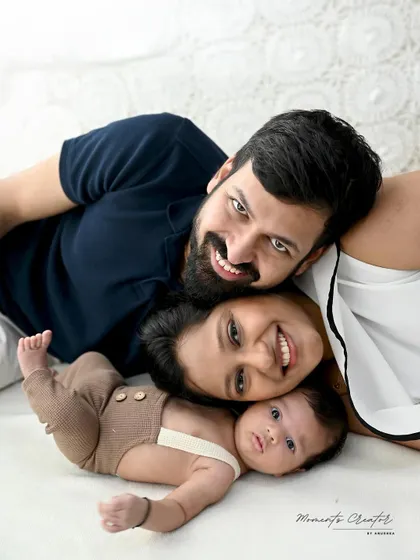 A fun and intimate family close-up. This overhead shot captures the happy faces of the parents and their wide-eyed newborn, creating a playful and loving memory.