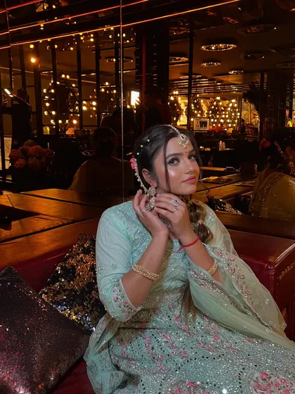 A playful pose showing the model adjusting her earring. This shot gives a good view of the diamond jewelry and the intricate braided hairstyle.