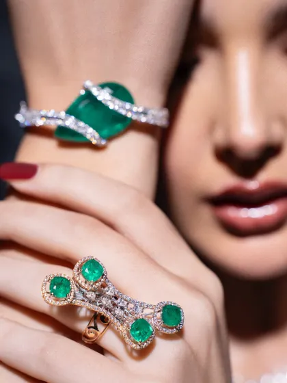 Another angle highlighting the bold emerald and diamond jewellery. The focus on the wrist and hand shows off the intricate design of the bracelet and ring, key pieces in this powerful, armored look.