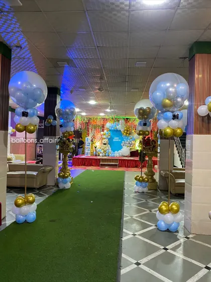 The entrance walkway for a baby's party, lined with balloon pillars topped with large transparent balloons, creating a grand welcome for guests.