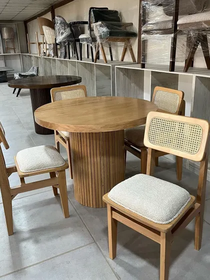 A close-up of the dining set, showing the texture of the bouclé fabric on the chairs and the detail of the table base.