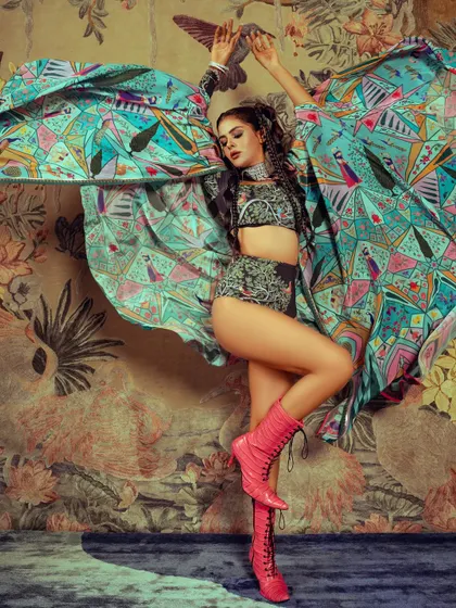 This dynamic shot from a celebrity editorial with Priyanka Chahar Choudhary showcases a bold, high-fashion look. The makeup was designed to stand out against the vibrant, patterned styling, featuring defined eyes and glowing skin that work with the powerful pose and intricate hairstyle.