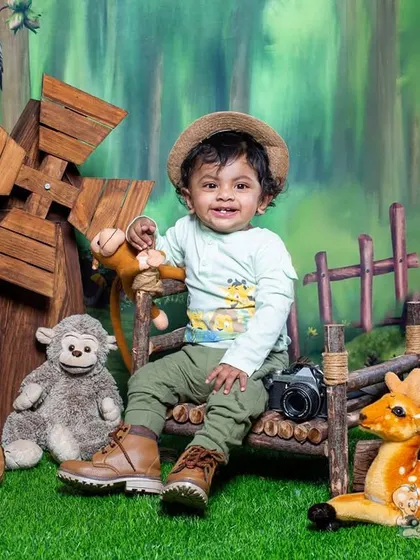 A little adventurer in a woodland setting. Surrounded by friendly animal props and a miniature windmill, this photo captures a sense of gentle exploration.