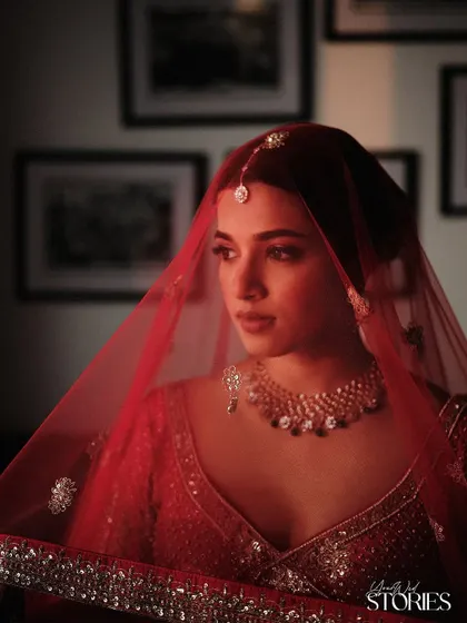 An artistic shot with the red veil creating a beautiful filter. This image highlights the flawless base and the way the makeup glows even in dramatic lighting.